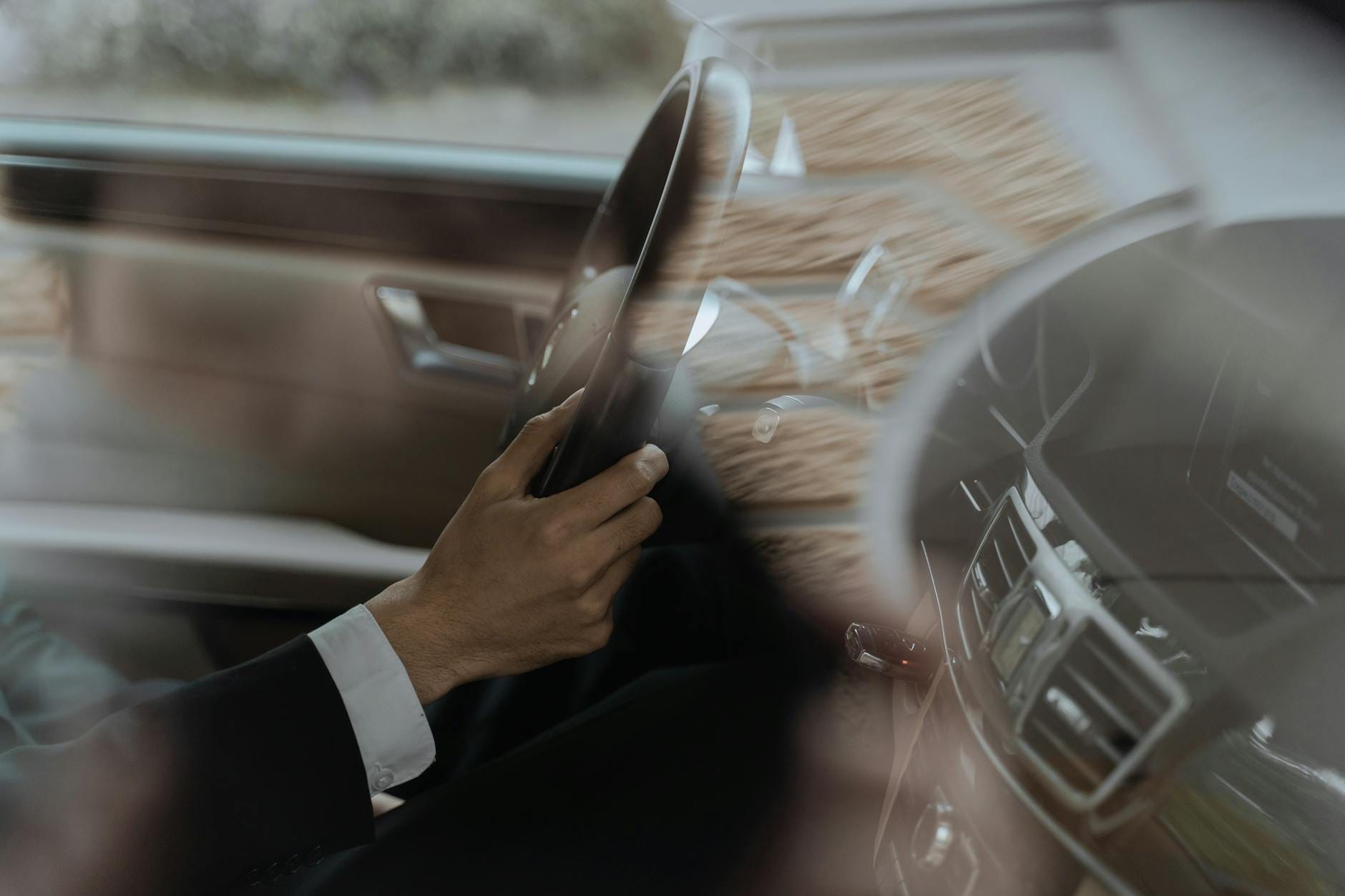 Dłoń kierowcy na kierownicy luksusowego auta we wnętrzu samochodu