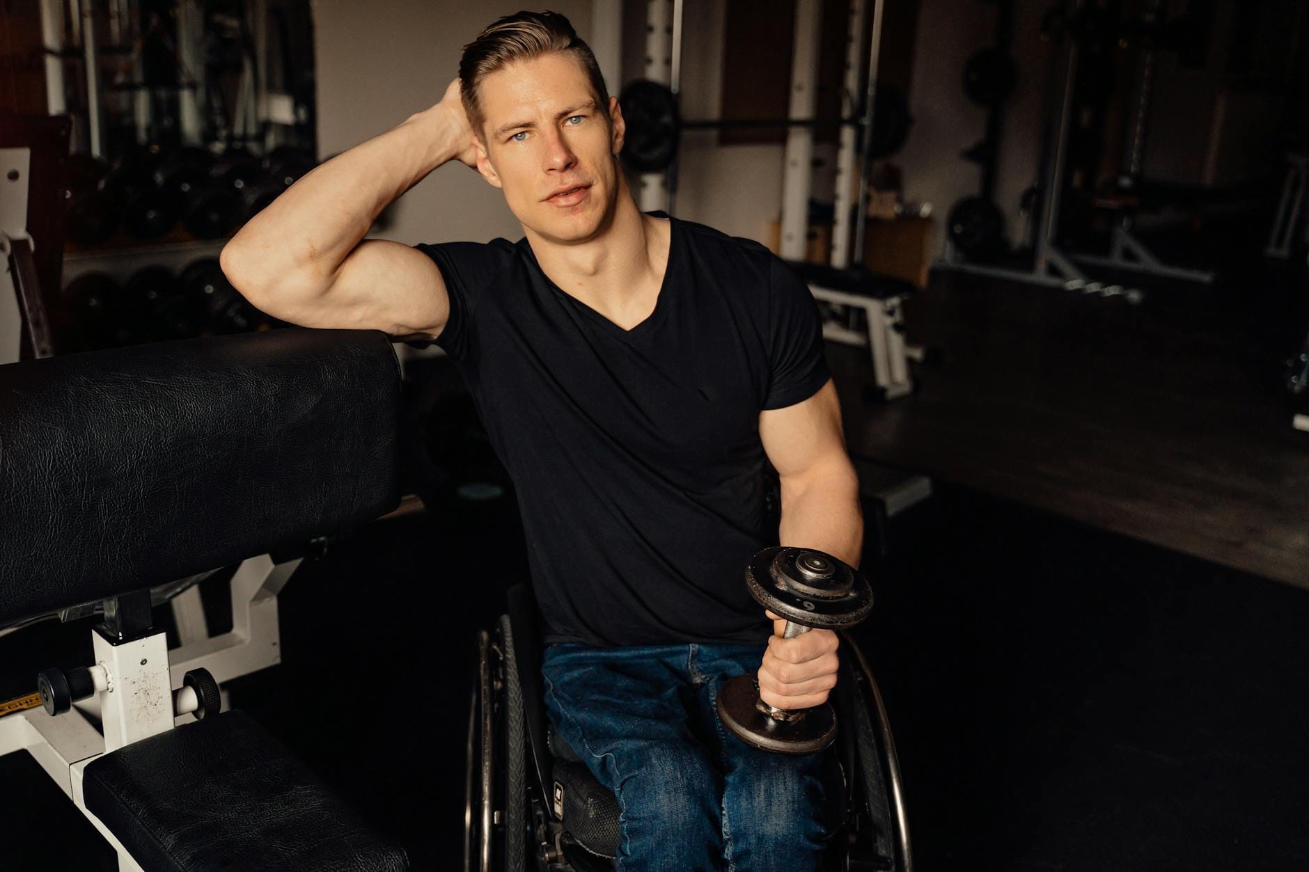 Mężczyzna na wózku inwalidzkim ćwiczy z hantlem na siłowni