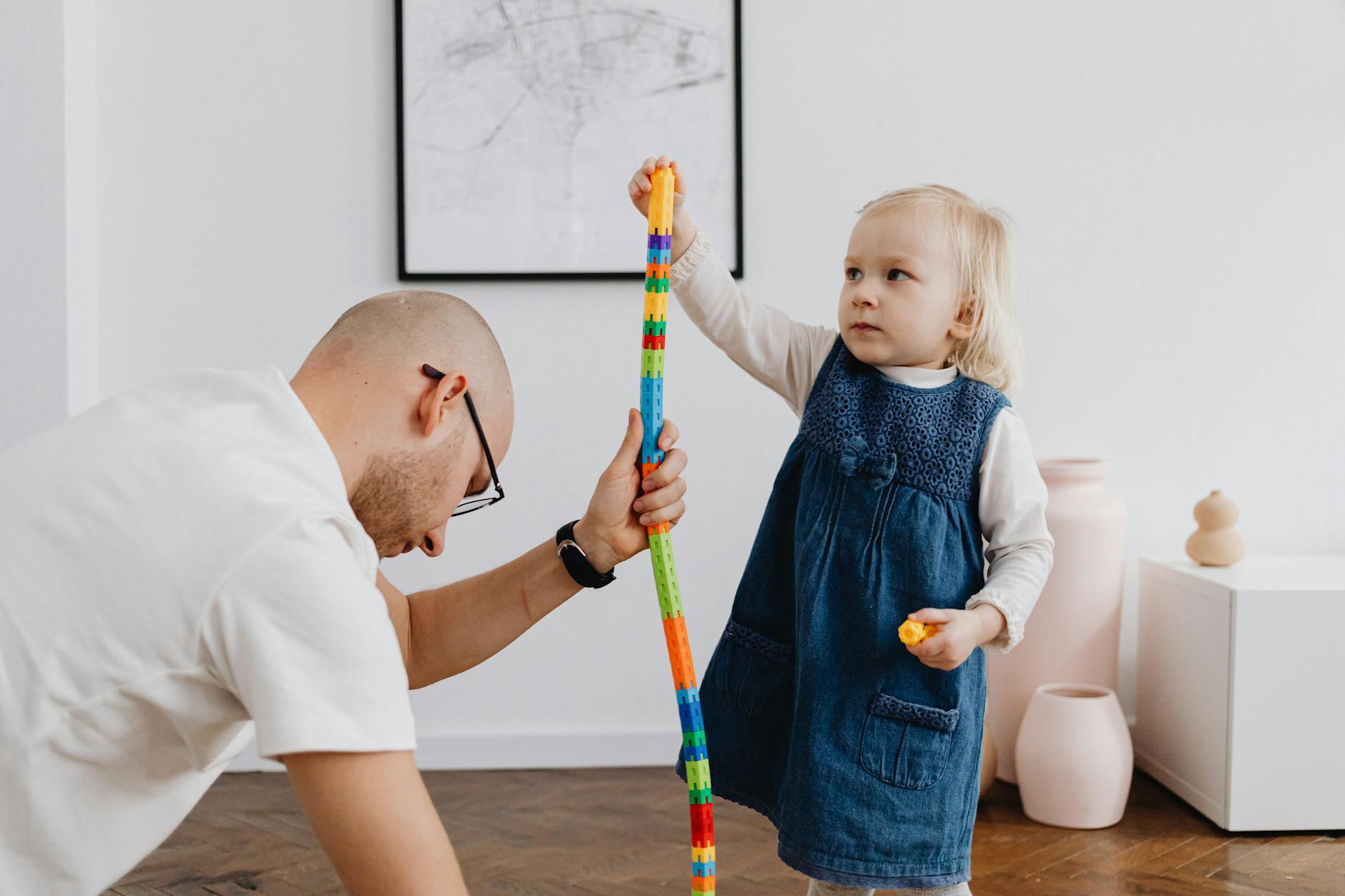 Tata bawi się z córeczką, układając kolorową wieżę z klocków