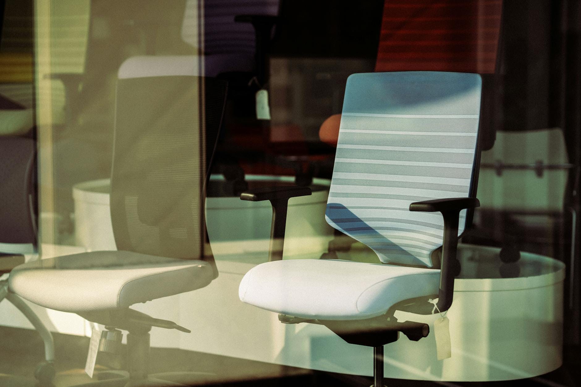 Ergonomiczne fotele biurowe za szklaną ścianą nowoczesnego biura