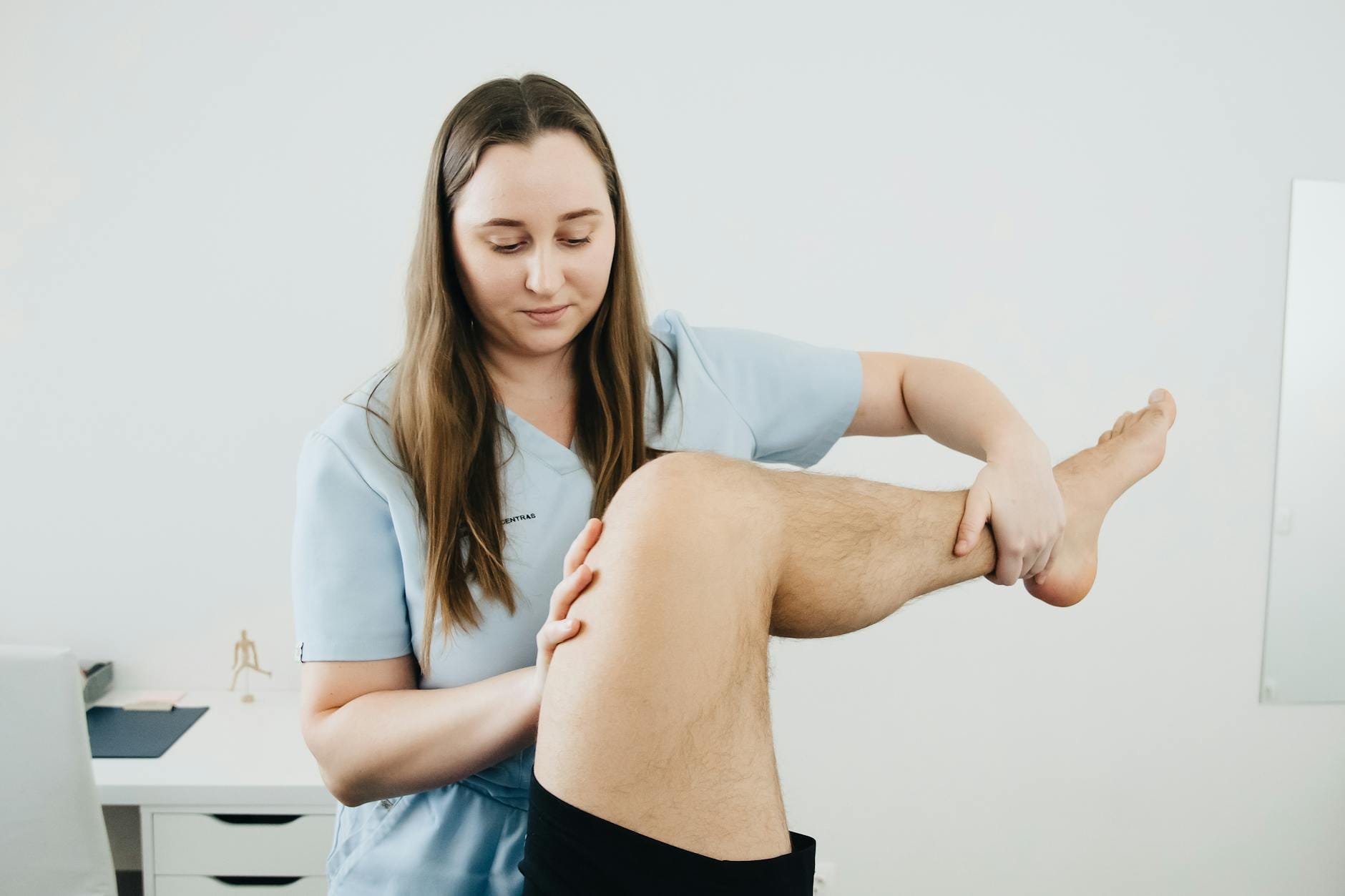 Fizjoterapeuta prowadzi ćwiczenia rehabilitacyjne nogi pacjenta