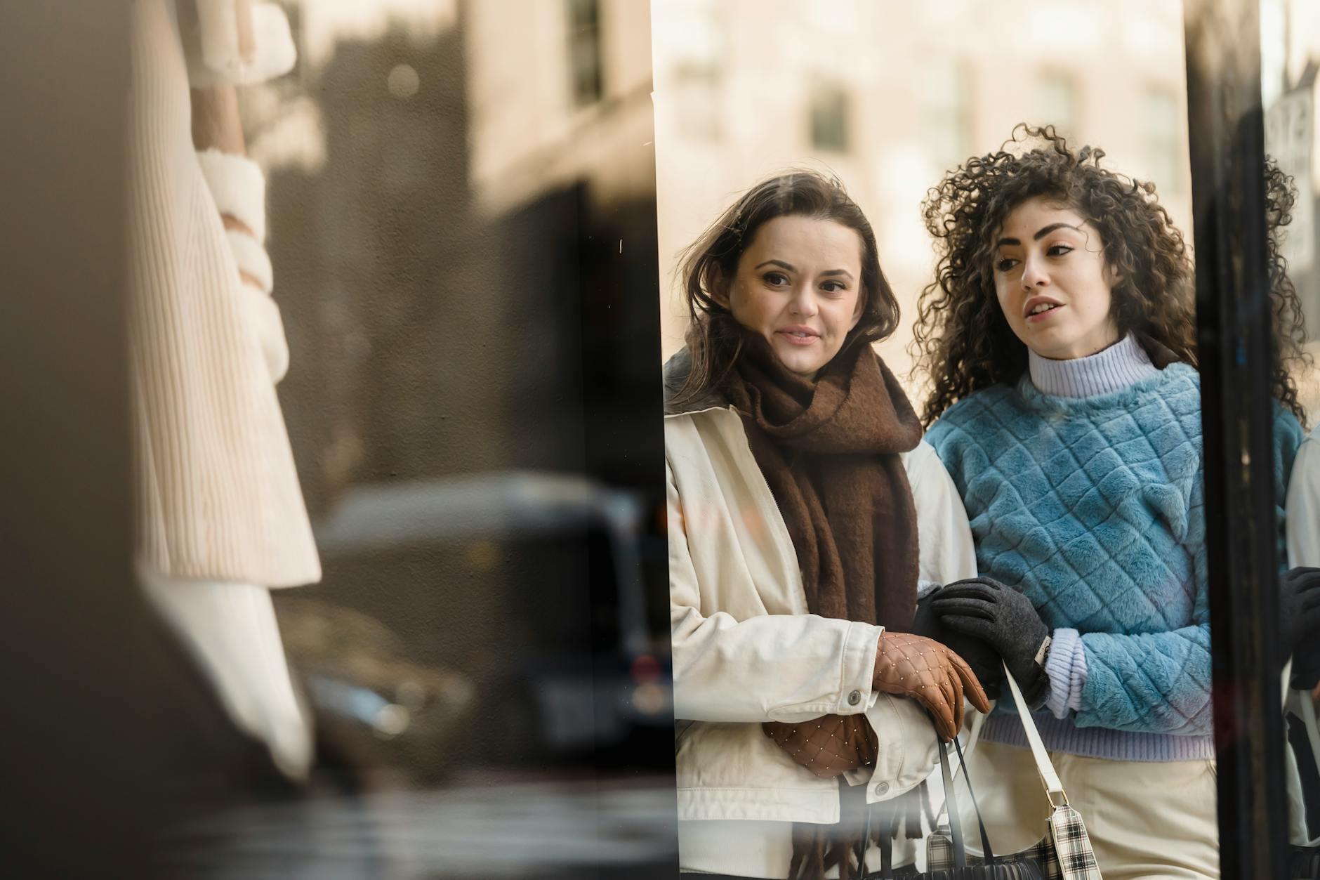 Młode kobiety oglądają jesienne ubrania w witrynie butiku moda
