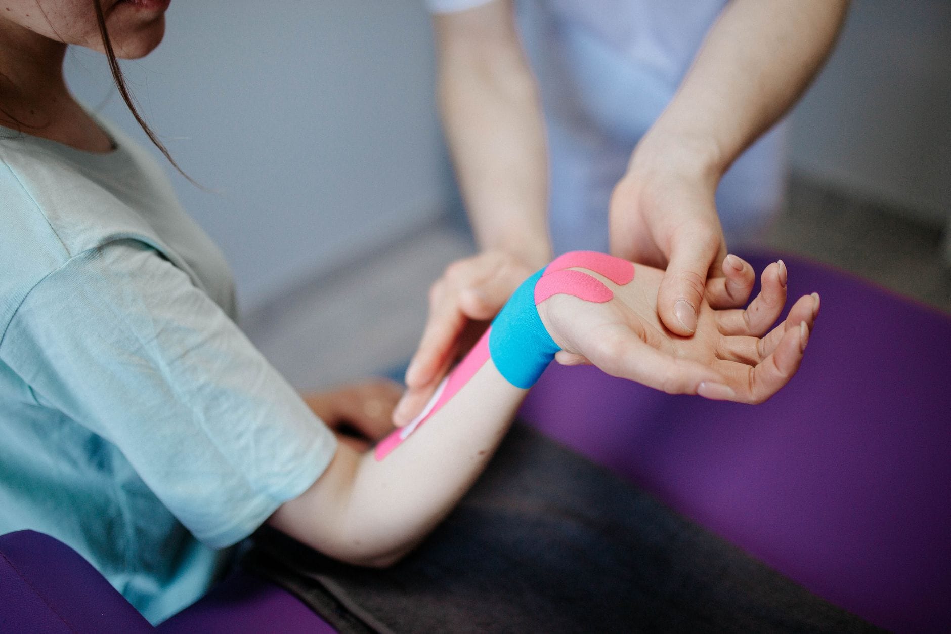Fizjoterapeuta nakleja taśmę kinesio na dłoń pacjenta
