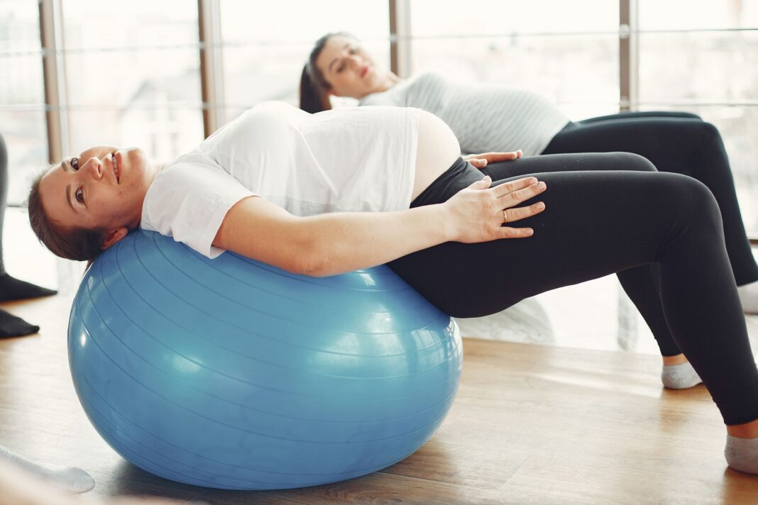 Kobiety w ciąży ćwiczą z piłkami fitness w sali Kobiety w ciąży ćwiczą z piłkami fitness w sali